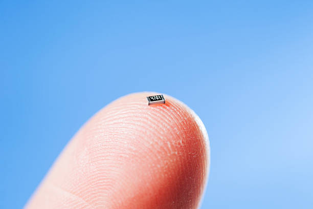 Componente SMD resistencia chip sobre la punta de un dedo mostrando su tamaño miniatura