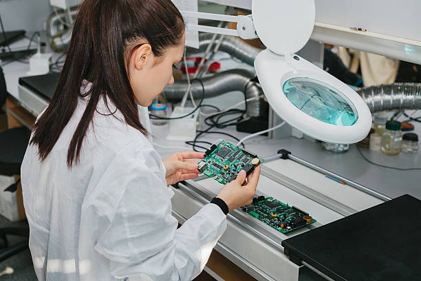 Técnica inspeccionando un PCB a medida con componentes montados en un laboratorio de fabricación electrónica